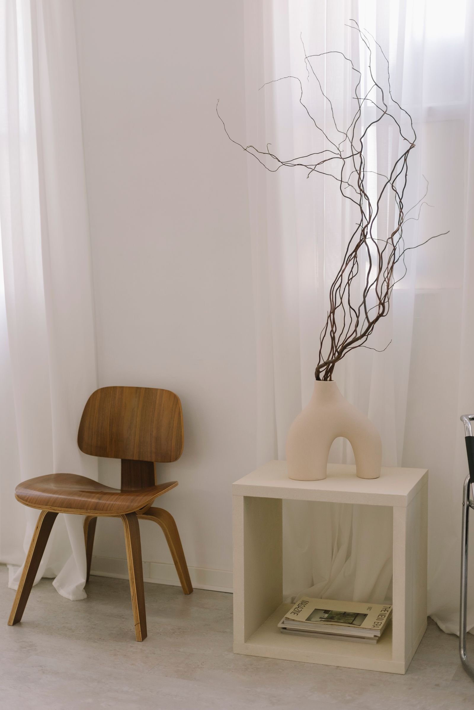 Minimalist home interior with a wooden chair, sheer curtains and simple decor