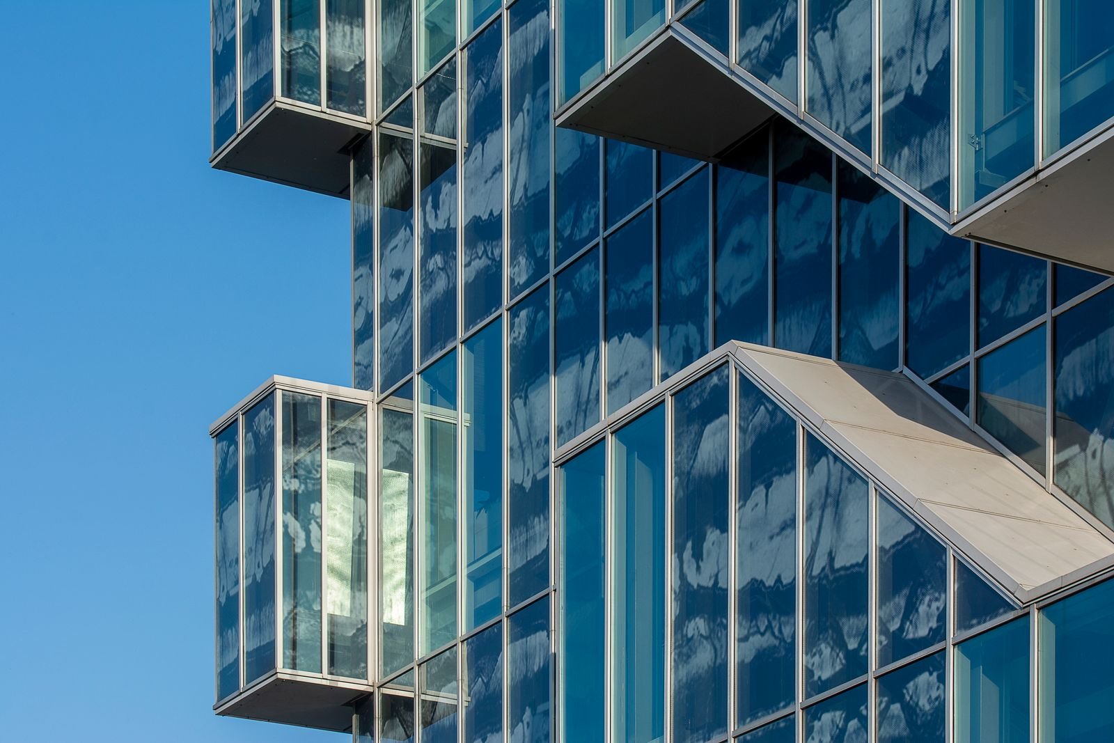 Modern glass facade reflecting sky and neighbouring buildings