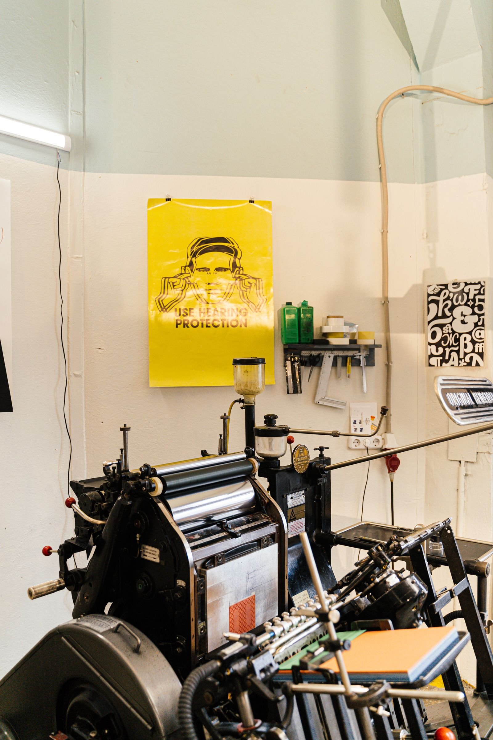 Design studio with a printing press and printed posters pinned around it