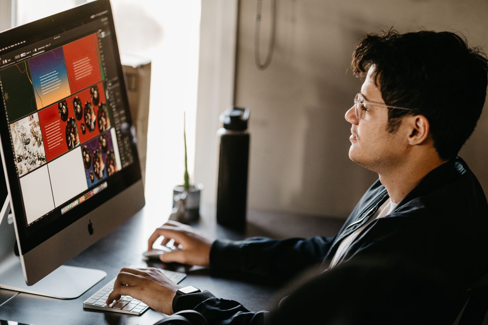 Graphic designer working at a computer with artwork open on screen