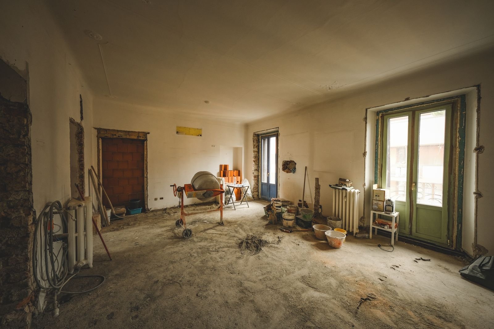 Empty room mid-renovation with bare walls, dust sheets and construction materials