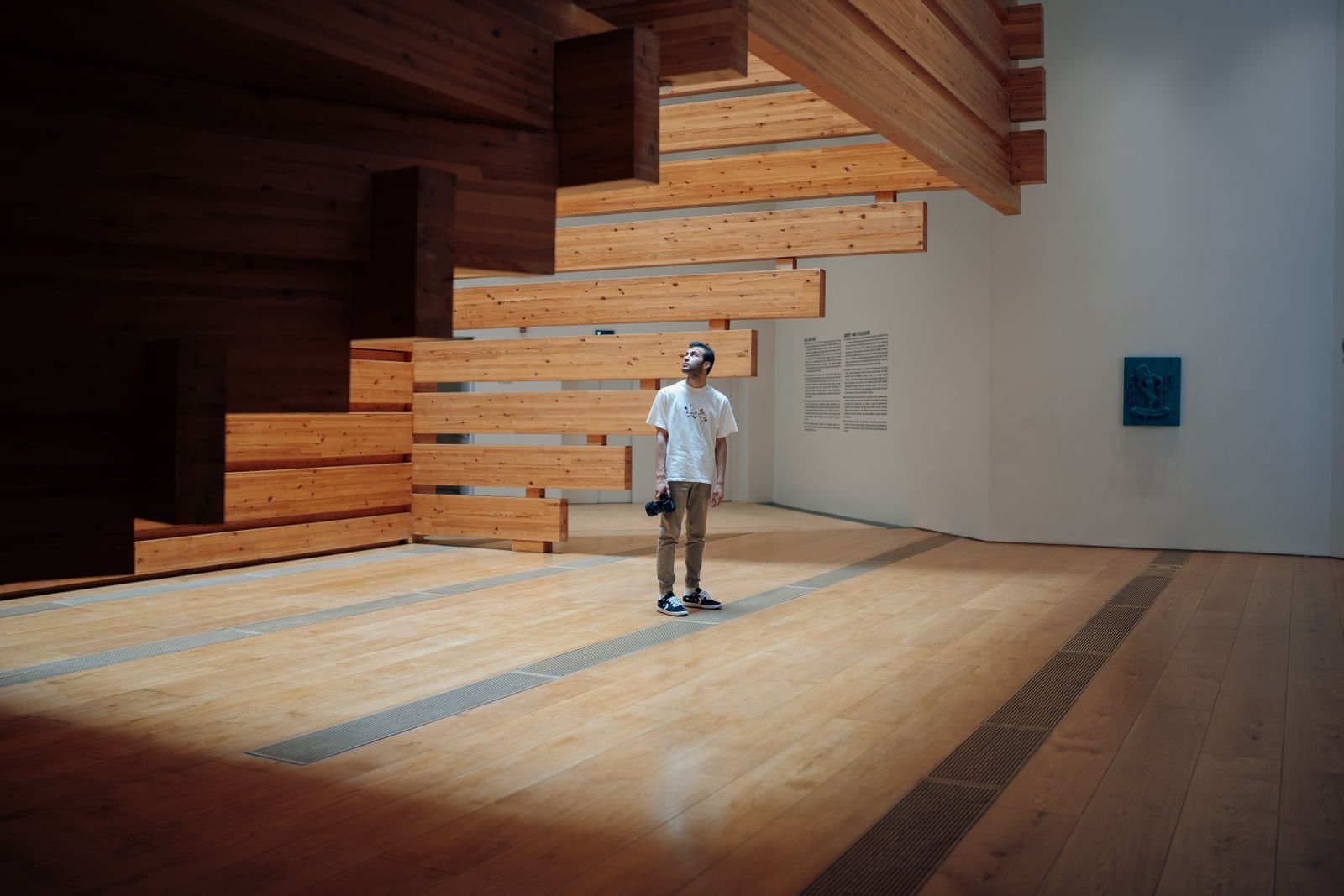 Visitor viewing a wooden installation at a contemporary art exhibition