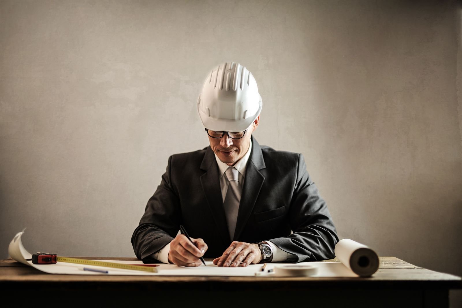 Designer at an office desk reviewing technical drawings and plans