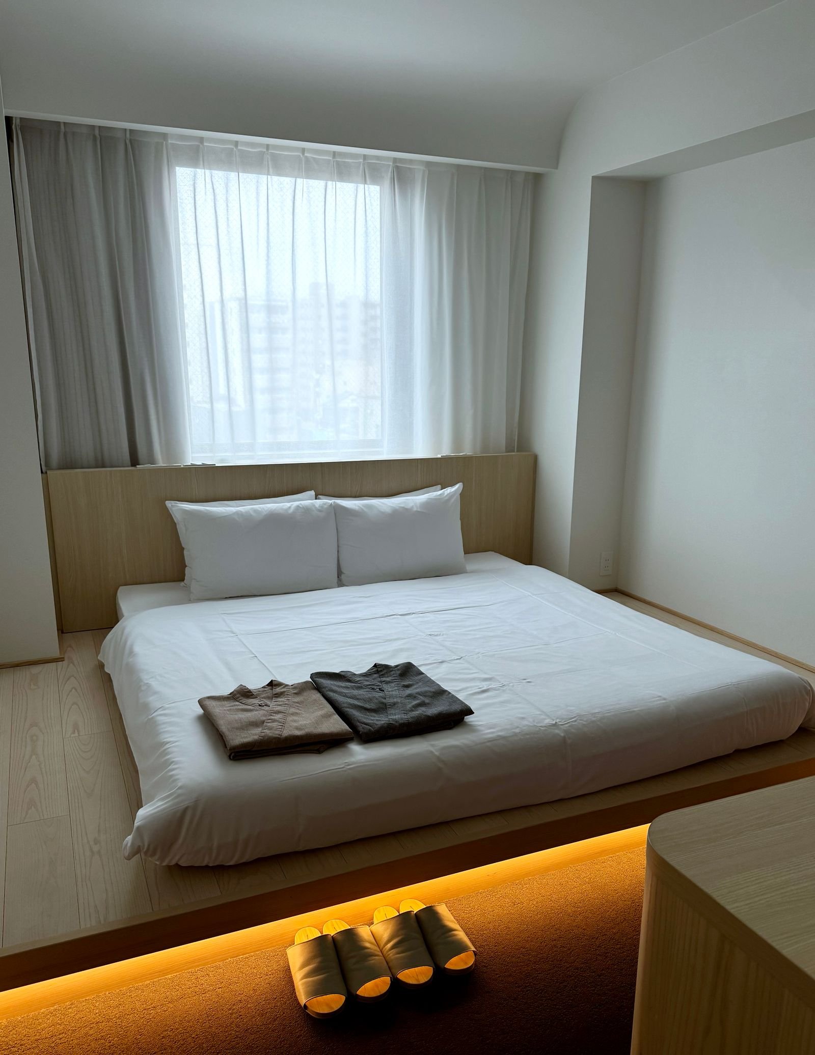 Minimalist Japanese-style bedroom with a low bed and pale wood finishes