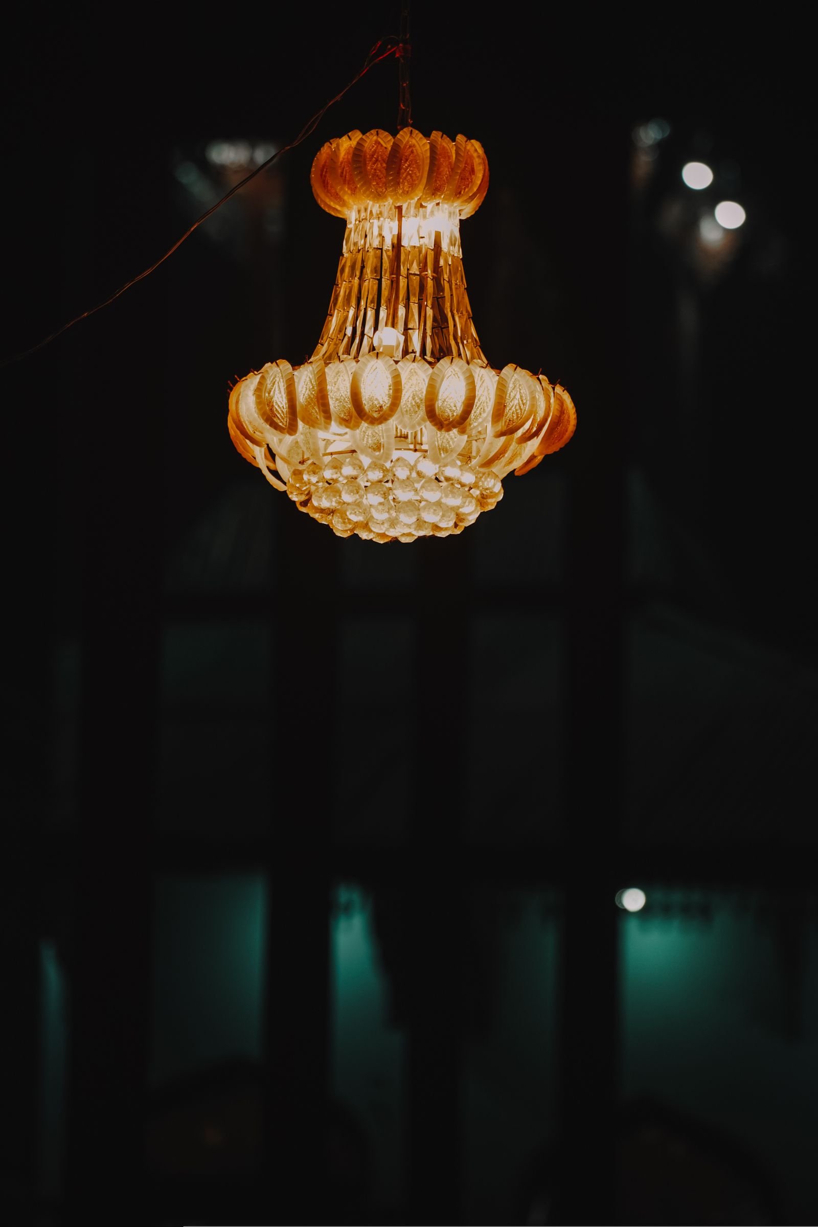 Ornate chandelier glowing above a dark, richly toned room