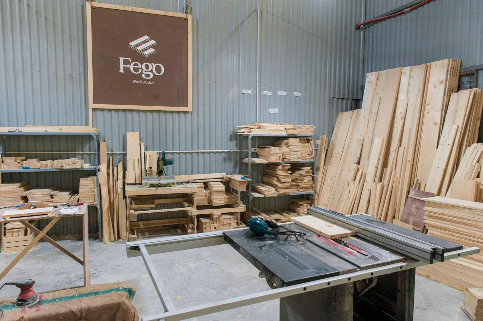 Interior of a woodworking shop with a table saw, stacked lumber and hand tools