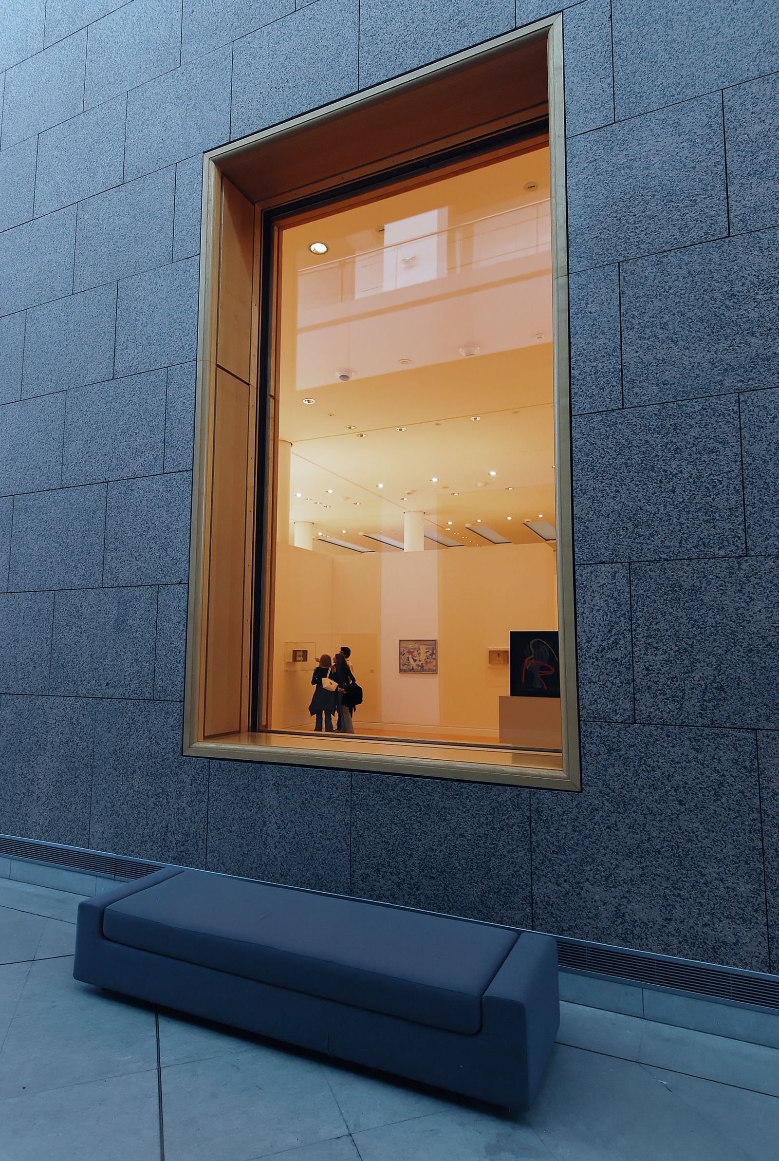 Large window looking into a modern gallery space with two visitors inside