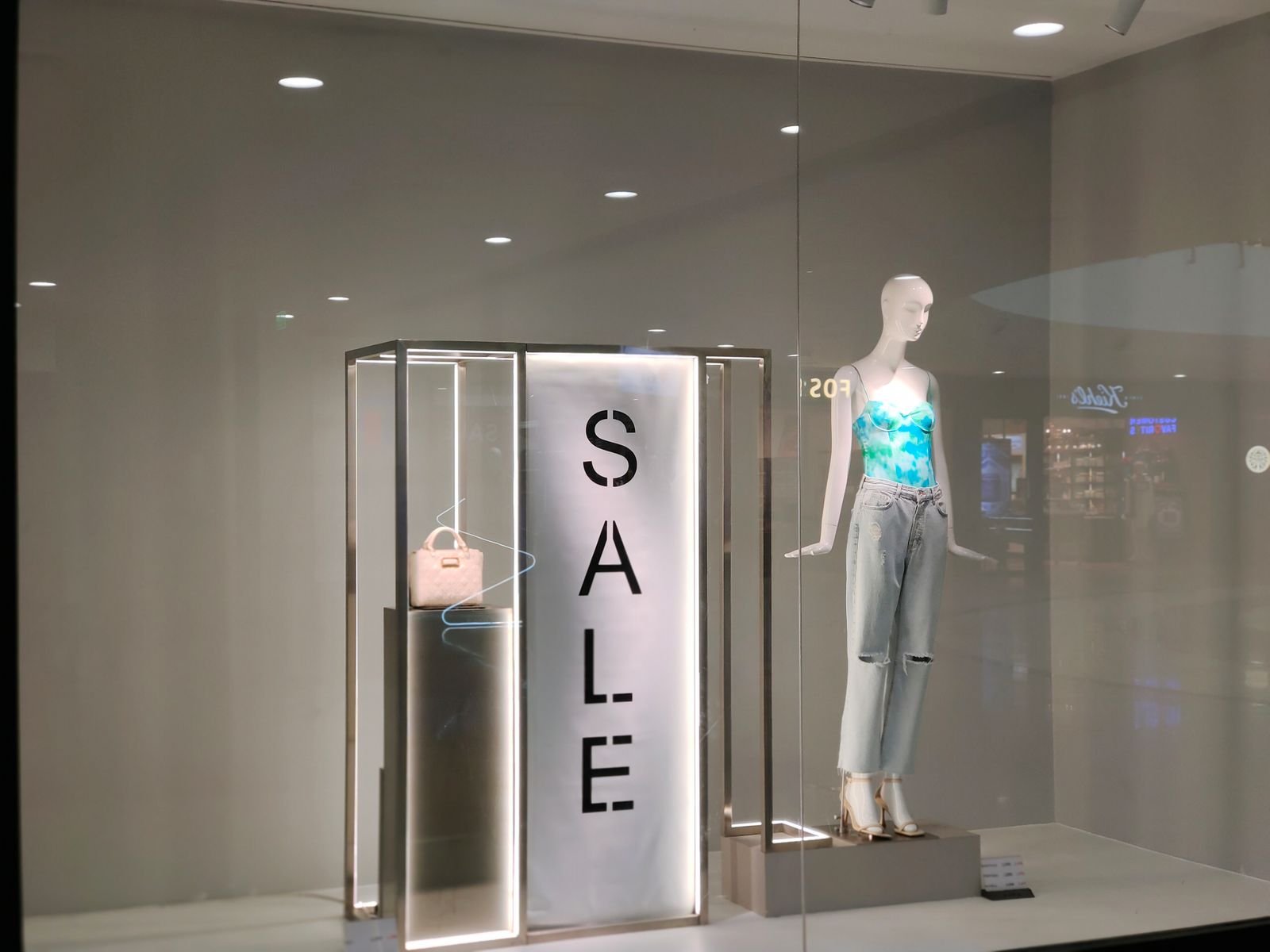 Clothing store window display with a dressed mannequin and a sale sign