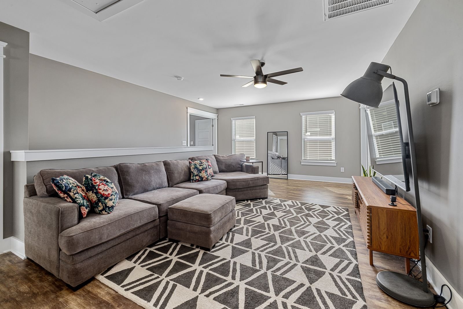 Cozy living room with a large sectional sofa, layered cushions and warm lamplight