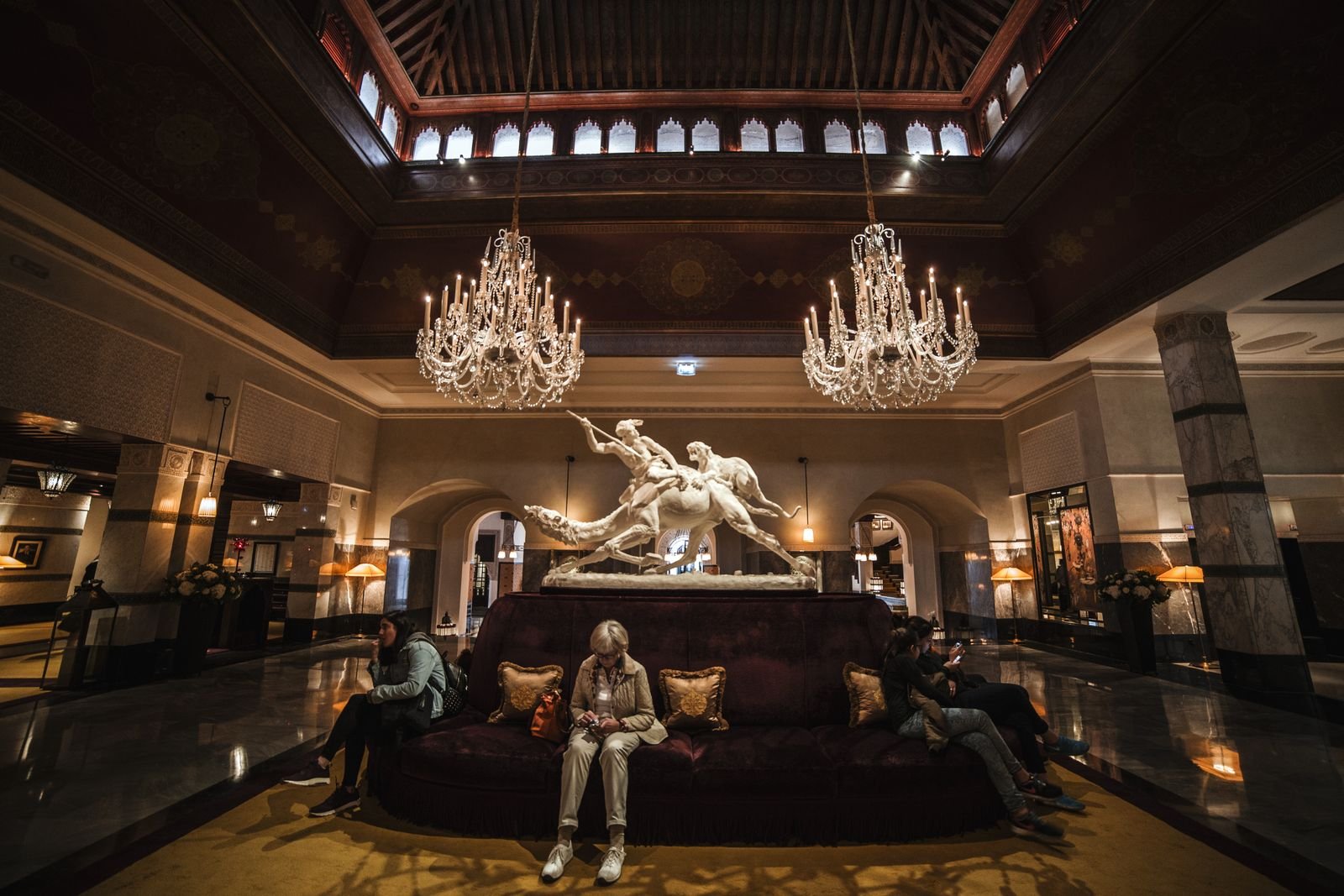 Spacious hotel lobby with chandeliers, sculpture and a formal seating arrangement