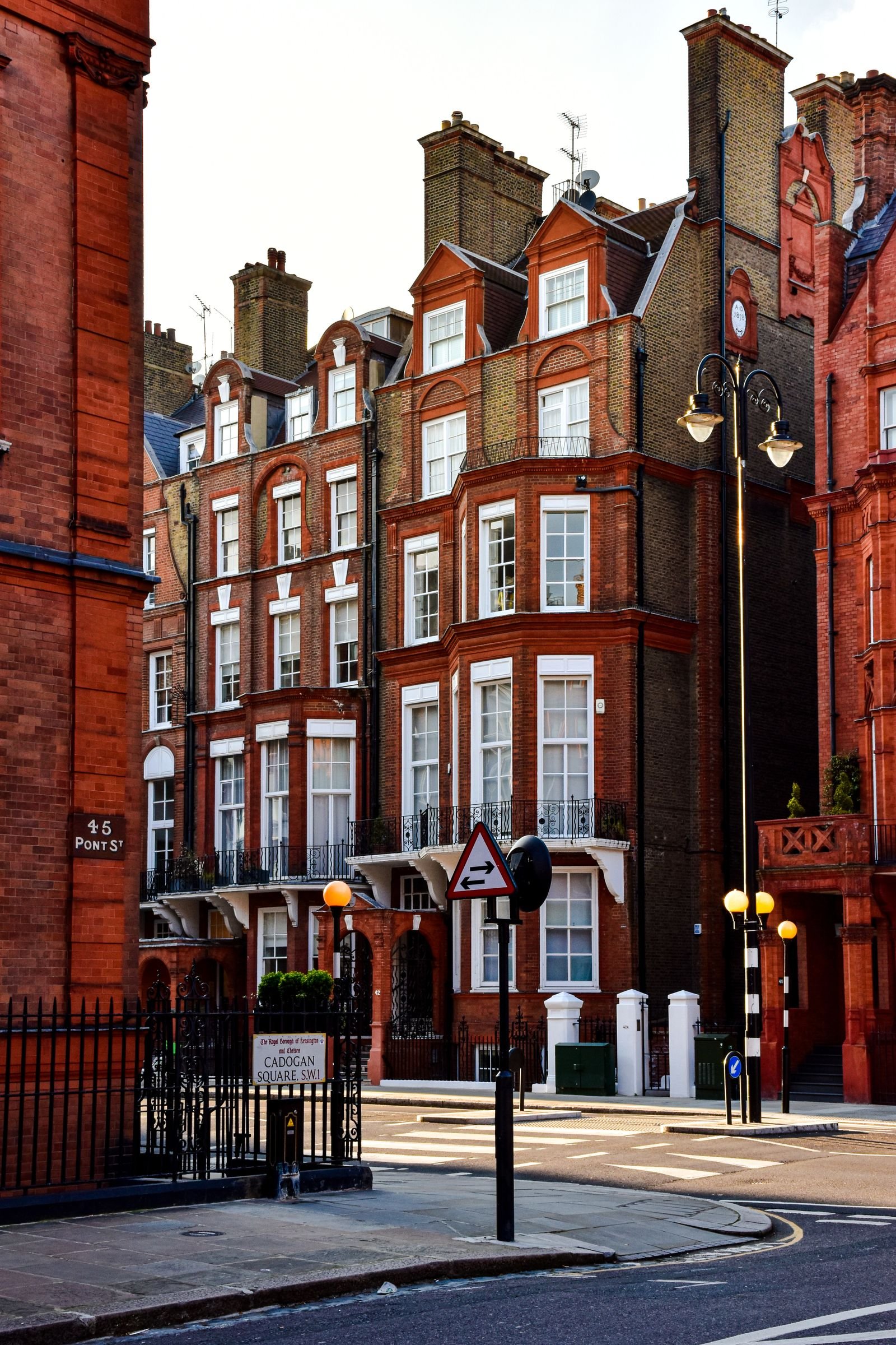 Row of red brick Victorian townhouses with bay windows along a street corner