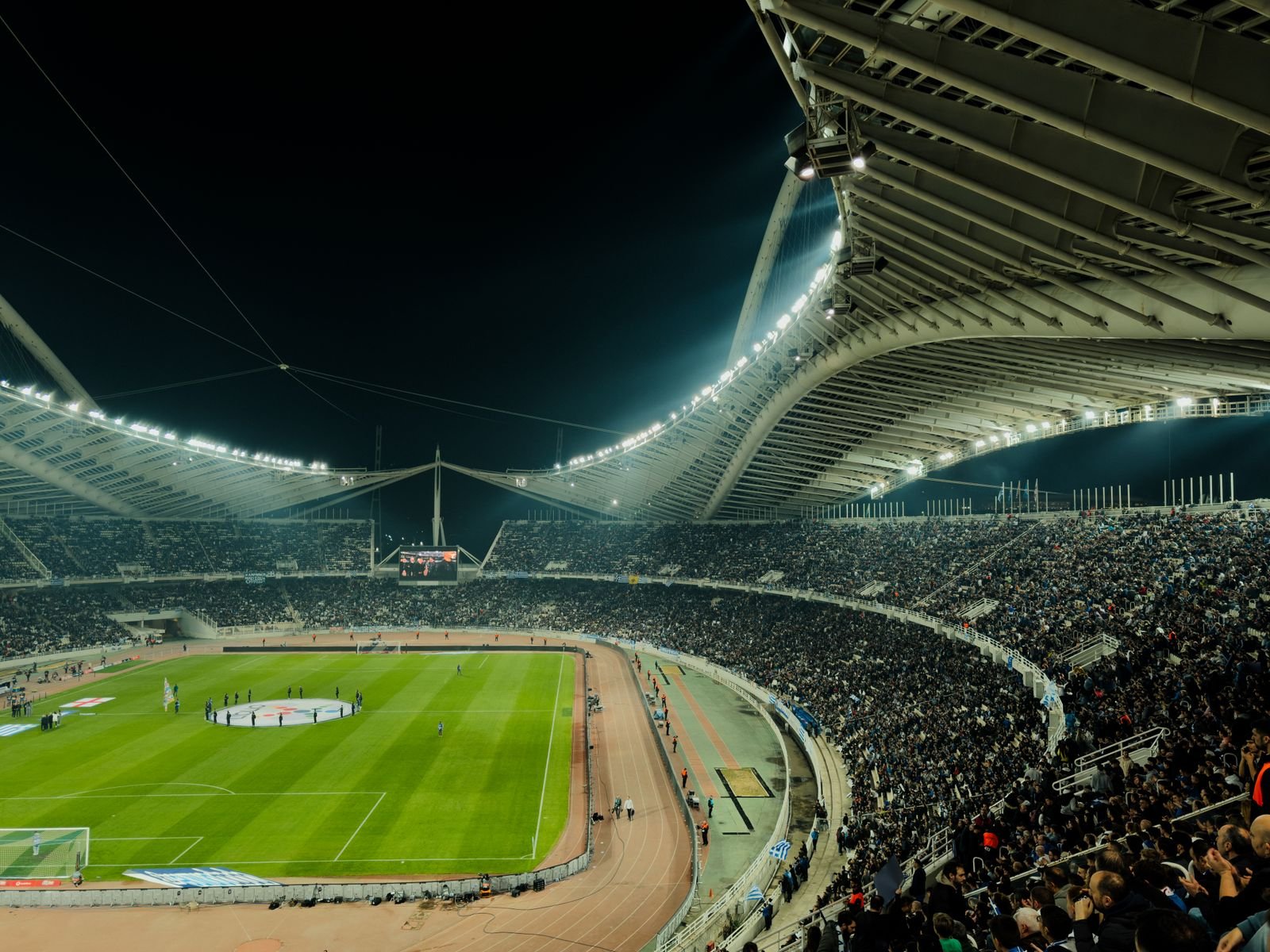 Floodlit soccer stadium at night packed with spectators