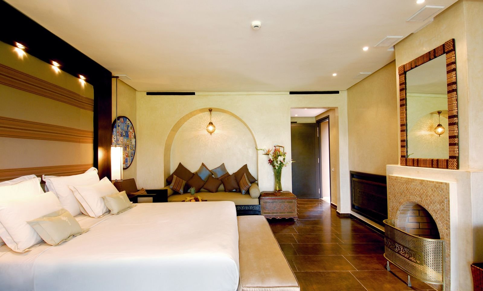 Elegant hotel room with a large bed, warm lighting and layered decor